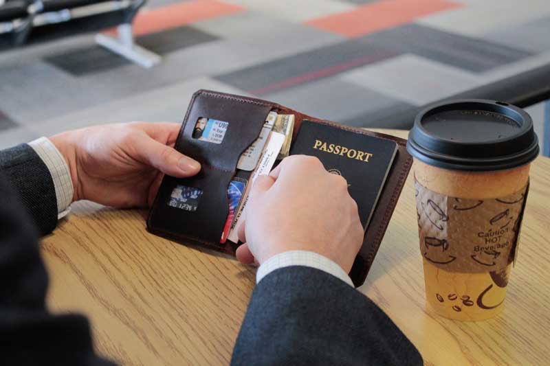 Traveler in Airport With His Passport Wallet Open Looking Through Tickets
