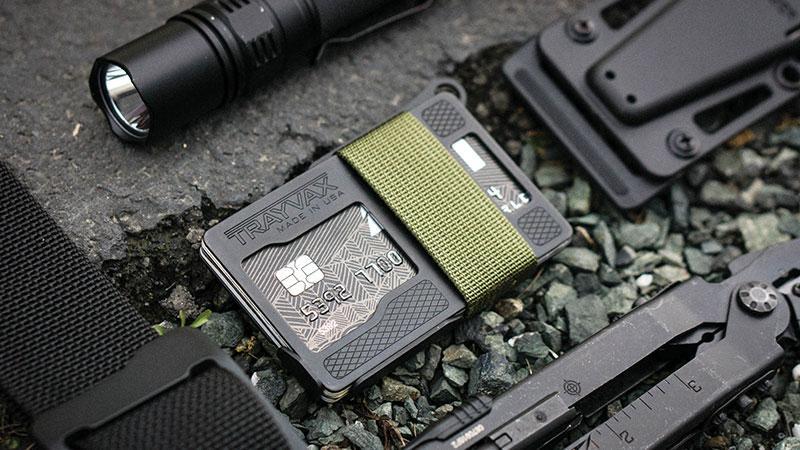 Black Armored Summit Wallet with OD Green Cinch Strap Around it Laying On Rocks With Other EDC Items around it