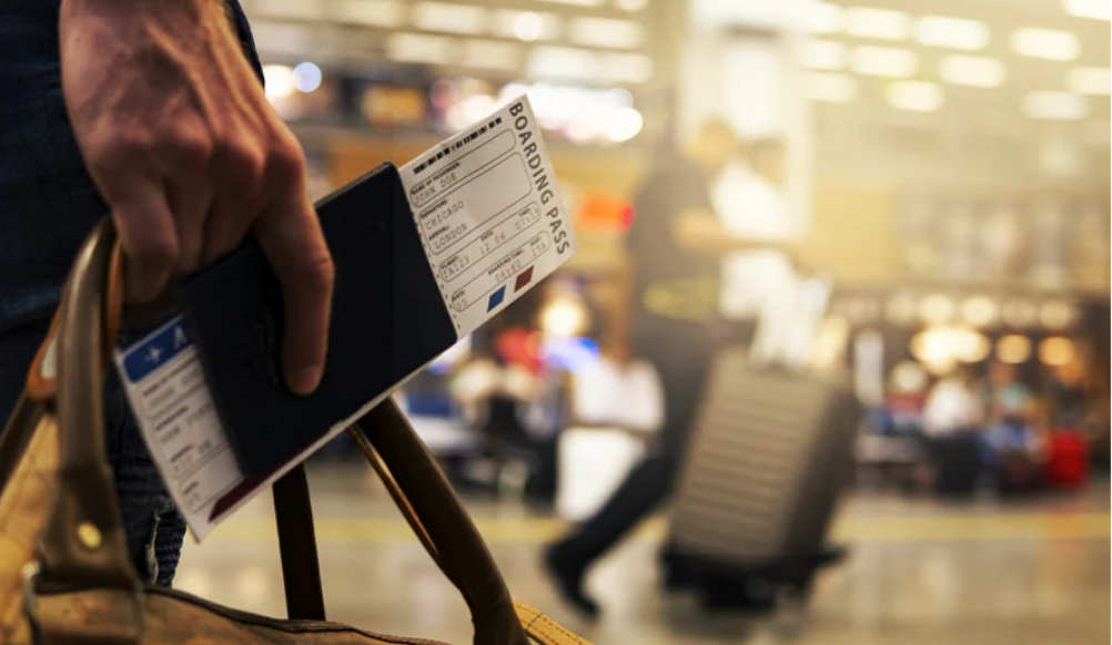 Walking through airport with Trayvax Passport Wallet in hand with flight tickets inside