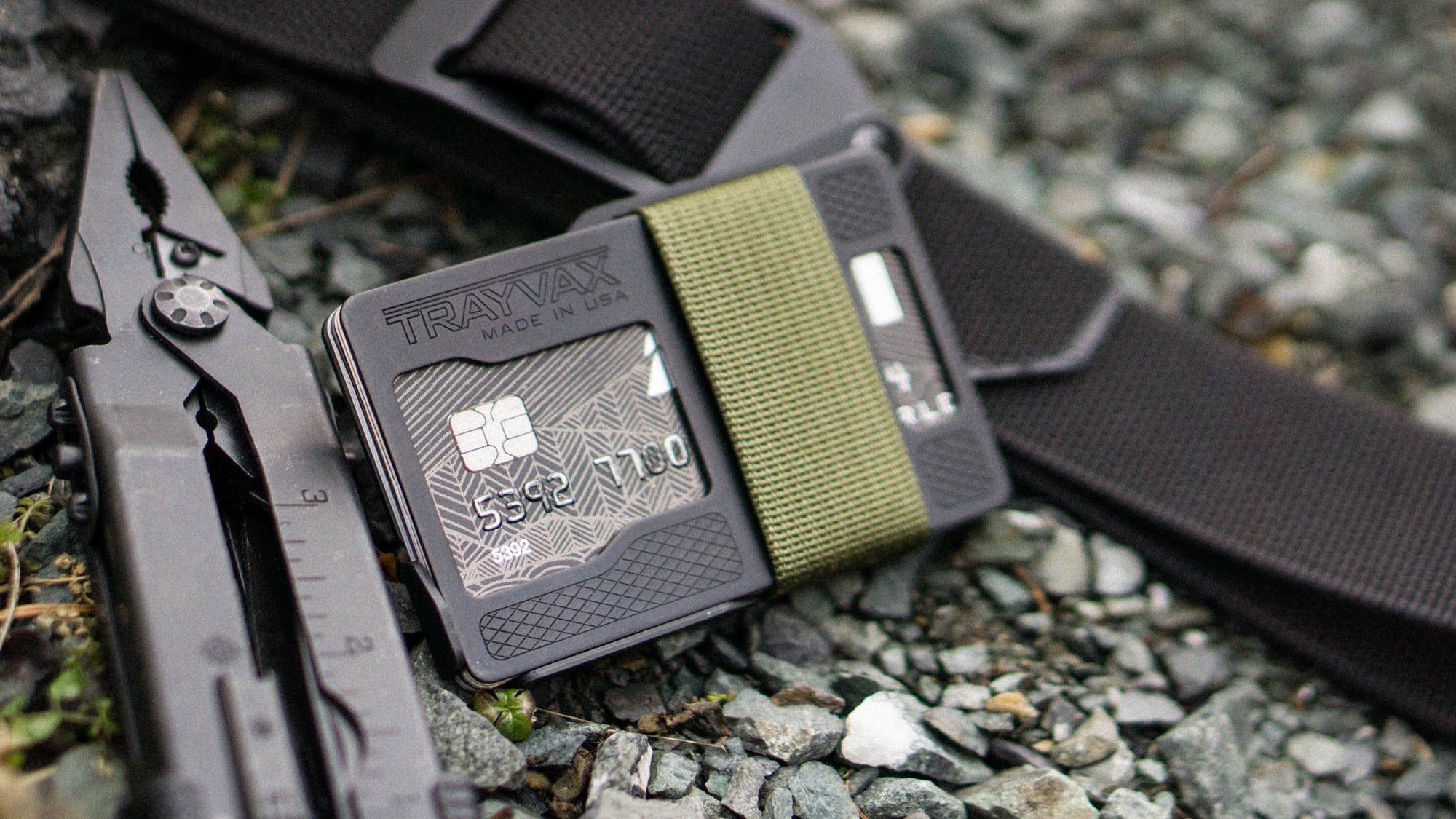 Armored Summit Wallet With OD Green Cinch Strap Laying on Rocks, Propped Up Agains Black Cinch Belt