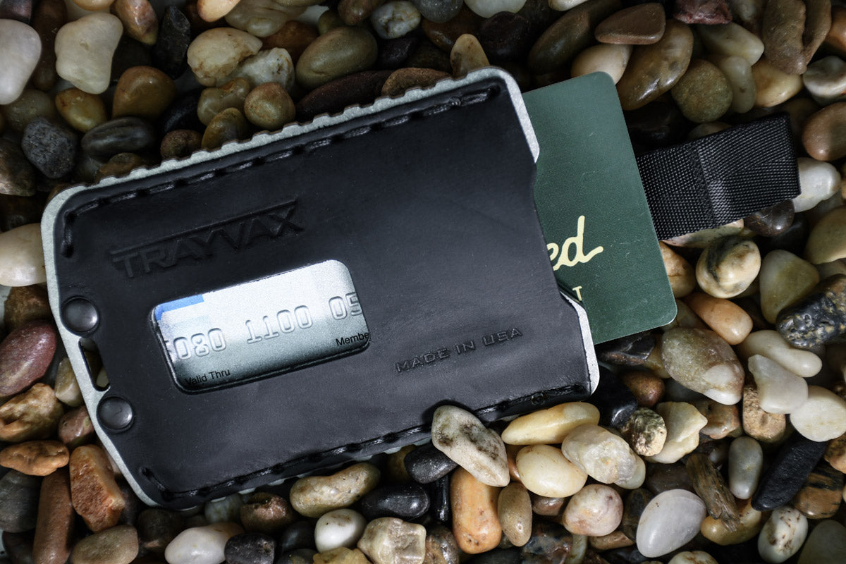 Stealth Black Horween Top-Grain Leather Wallet Laying on Rock Pebbles With Card Slipped Out